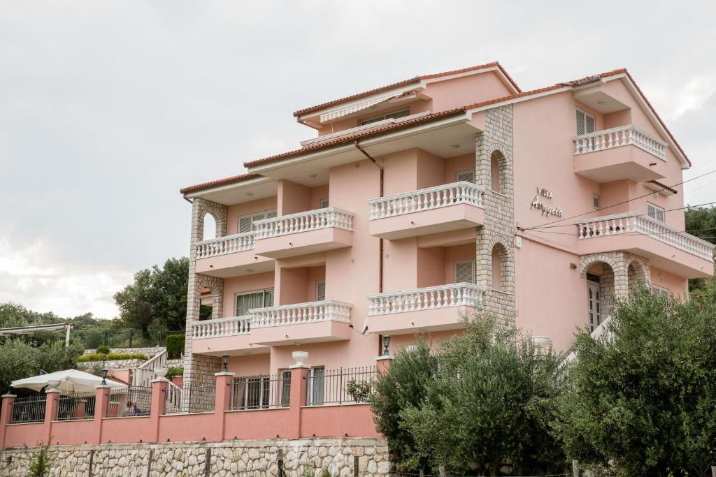 a pink building with balconies and a fence at Villa Anggela in Supetarska Draga