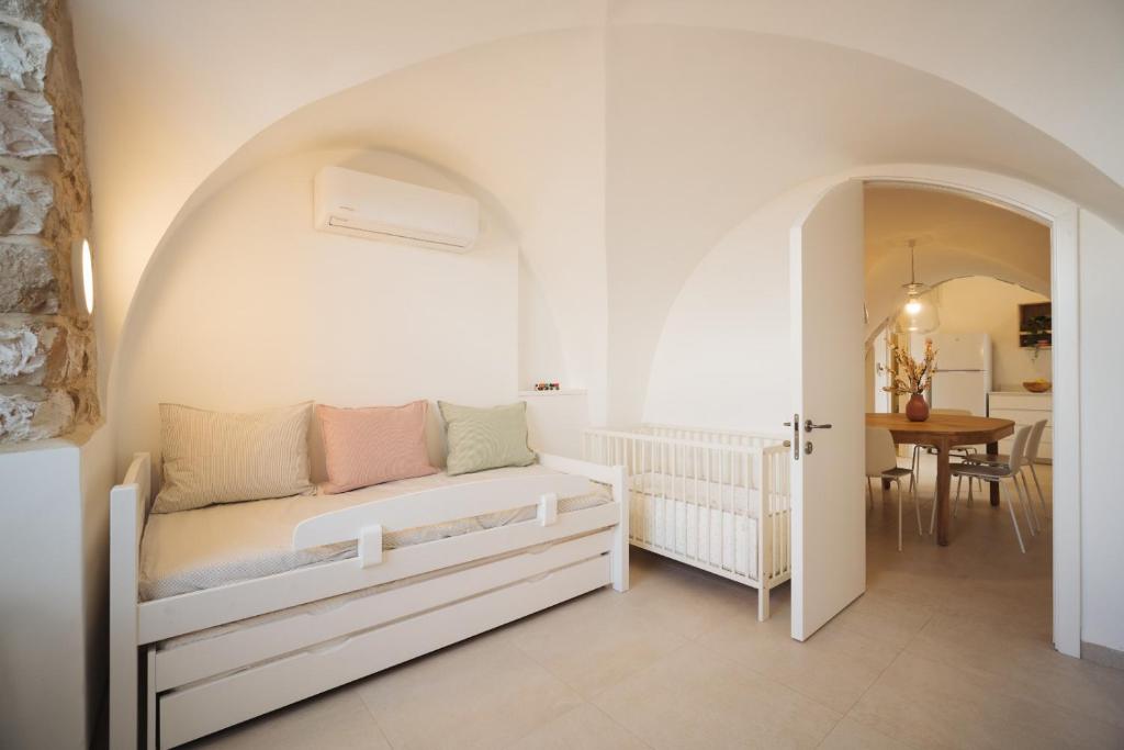a white bedroom with a bed and a table at חקל תפוחין in Safed