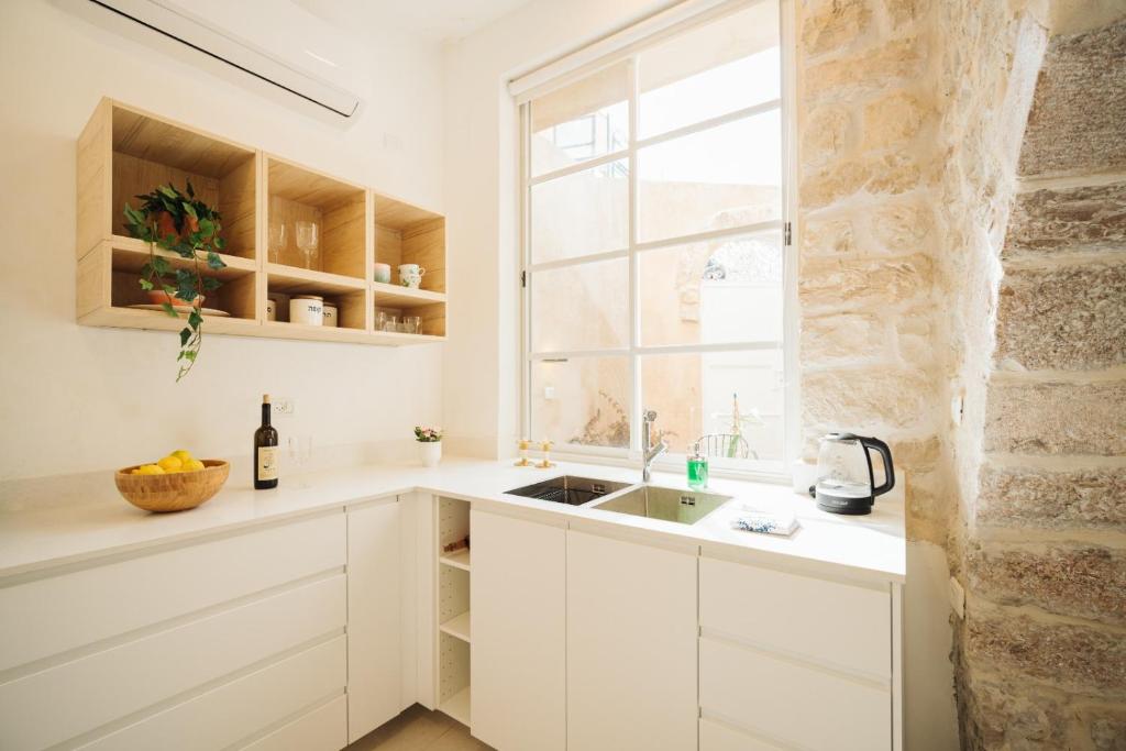 a white kitchen with a sink and a window at חקל תפוחין in Safed