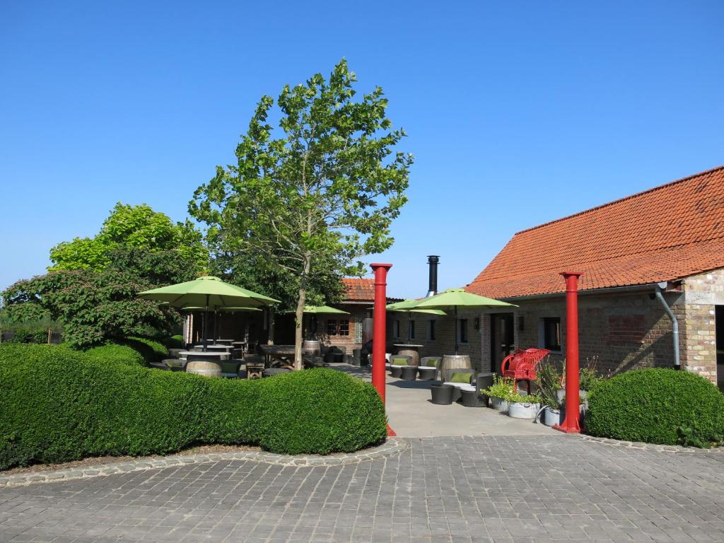 ein Gebäude mit einer Terrasse mit einem Baum und Büschen in der Unterkunft Hoeve Chartreuse in Brügge