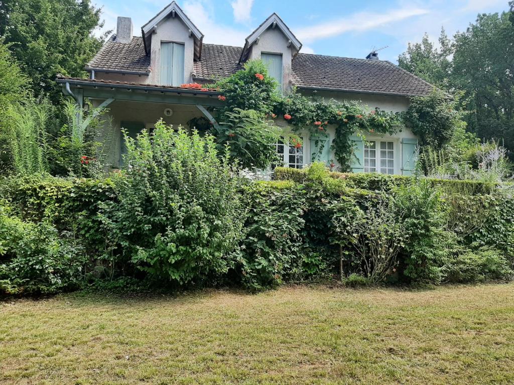 Ein Haus mit Büschen davor. in der Unterkunft L'orée du bois in Luzech