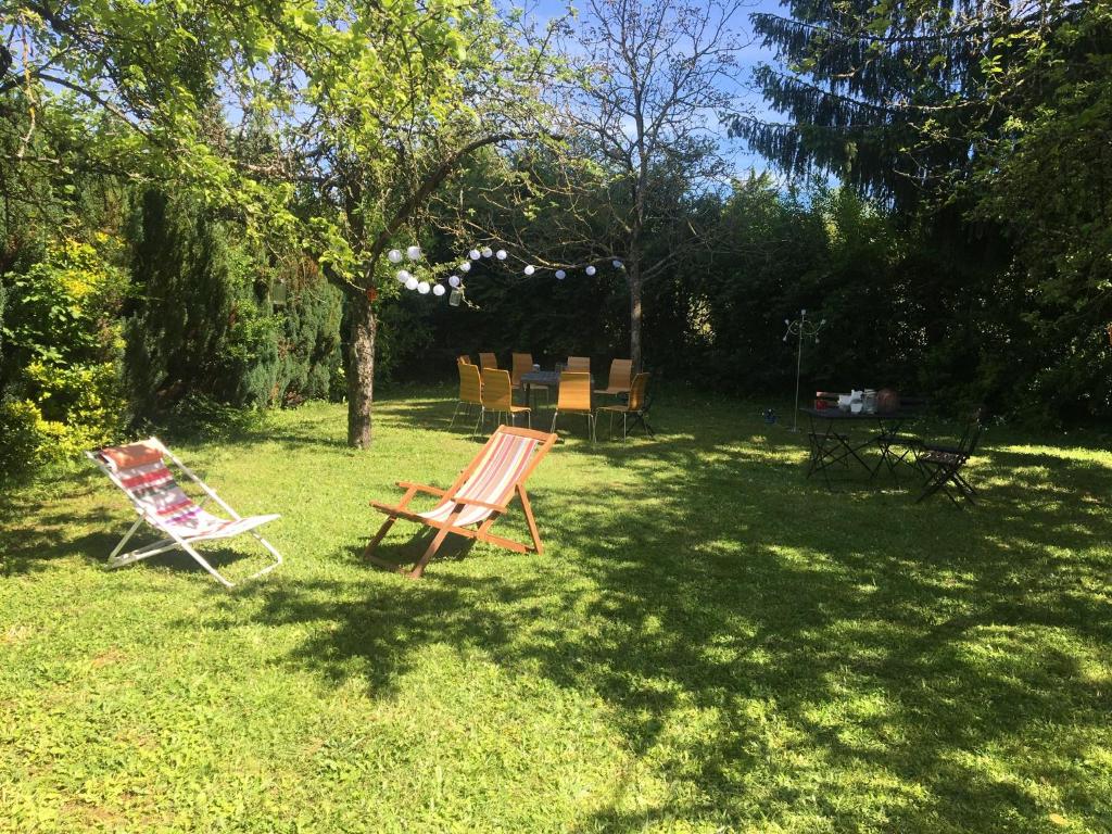 zwei Stühle im Gras im Garten in der Unterkunft L'entre 2 Lyon Grenoble - Villa avec Jacuzzi in Izeaux