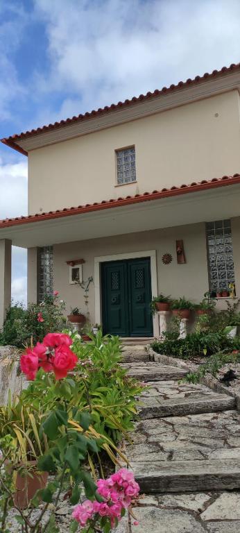 a house with a green door and some pink flowers at Beco do Patalugo in Salir de Matos
