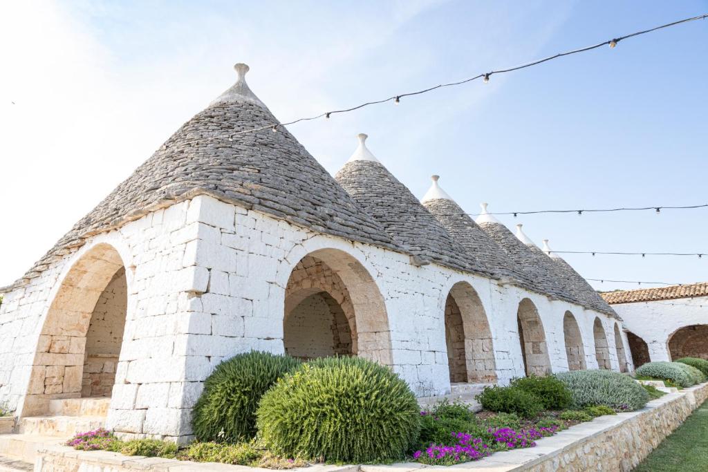 un edificio de ladrillo blanco con arcos y plantas en Masseria Pilano, en Crispiano