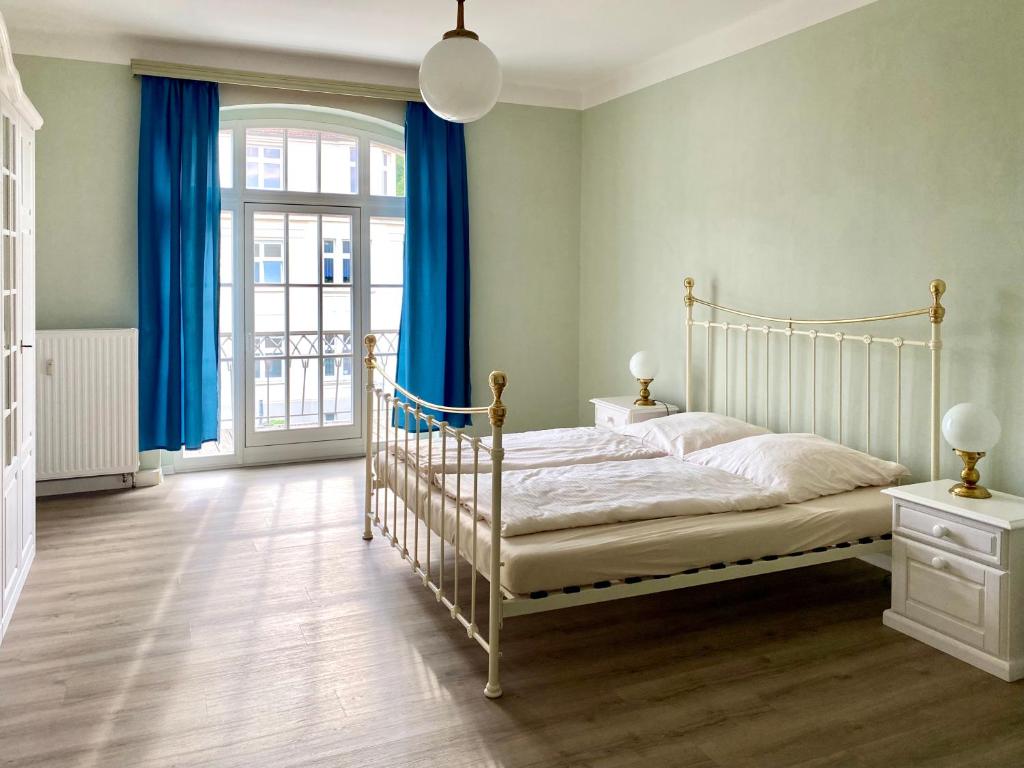 1 dormitorio con cama blanca y cortinas azules en FeWo Art Deco, en Zittau