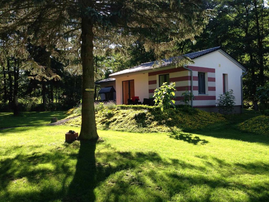 ein kleines weißes Haus mit einem Baum im Gras in der Unterkunft Kunstpark Reinhardsbrunn in Friedrichroda