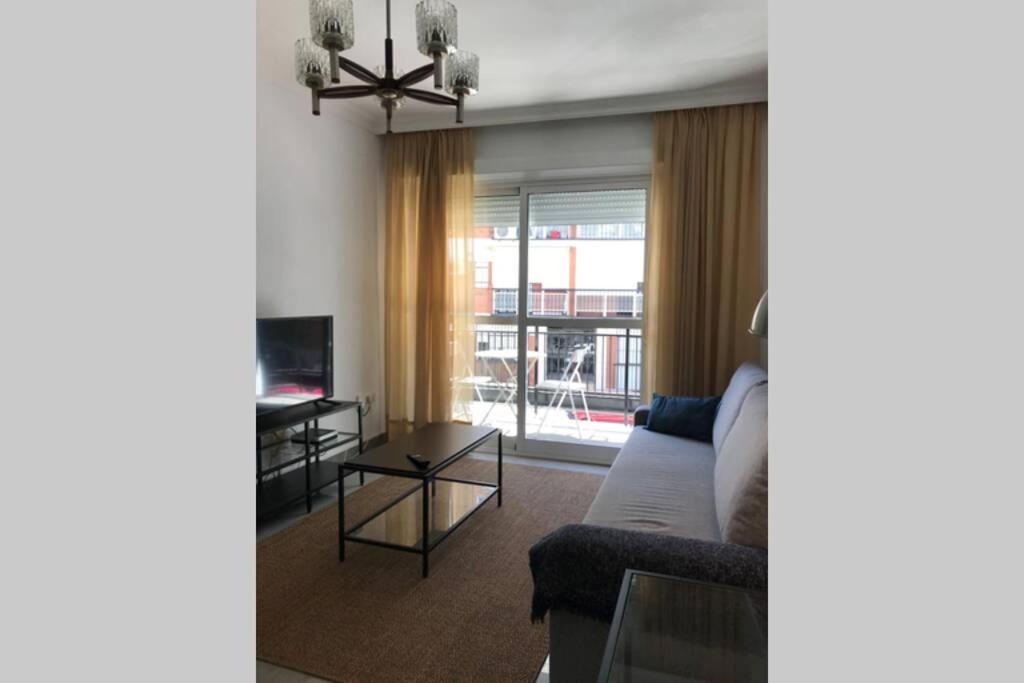 una sala de estar con un sofá y una mesa en AC TRIANA numancia, en Sevilla