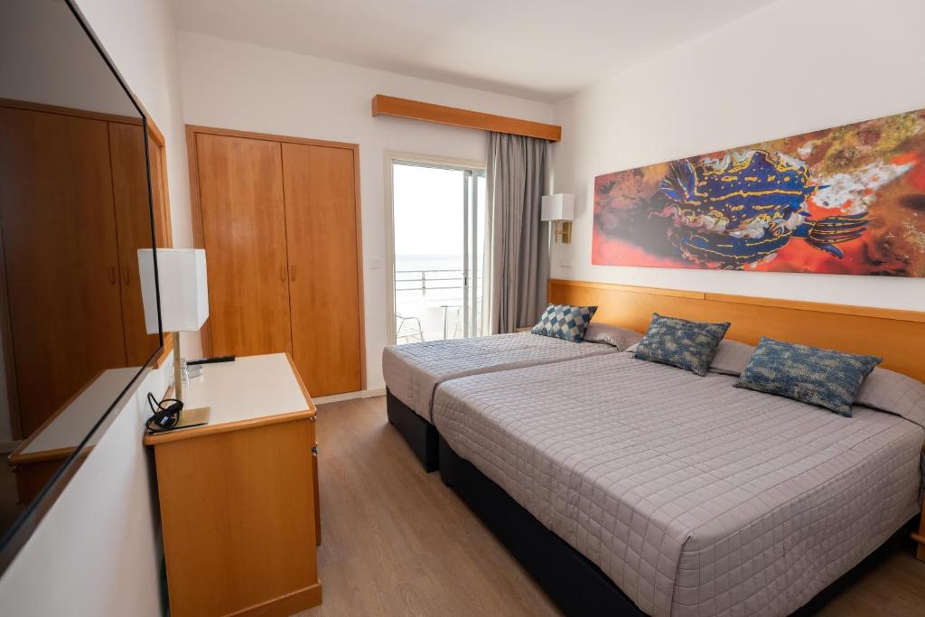 a hotel room with a bed and a window at Tylos Beach Hotel in Kato Pyrgos