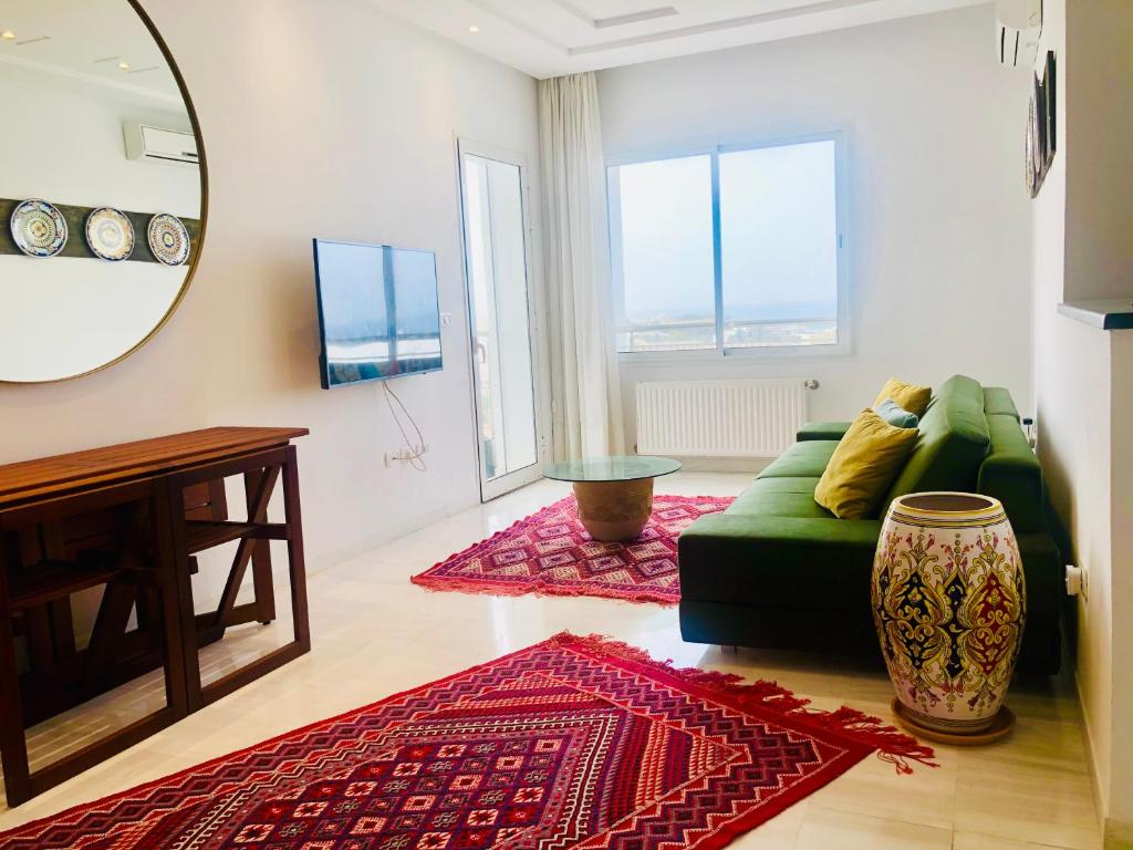 Byblos Sousse في سوسة: غرفة معيشة مع أريكة خضراء ومرآة