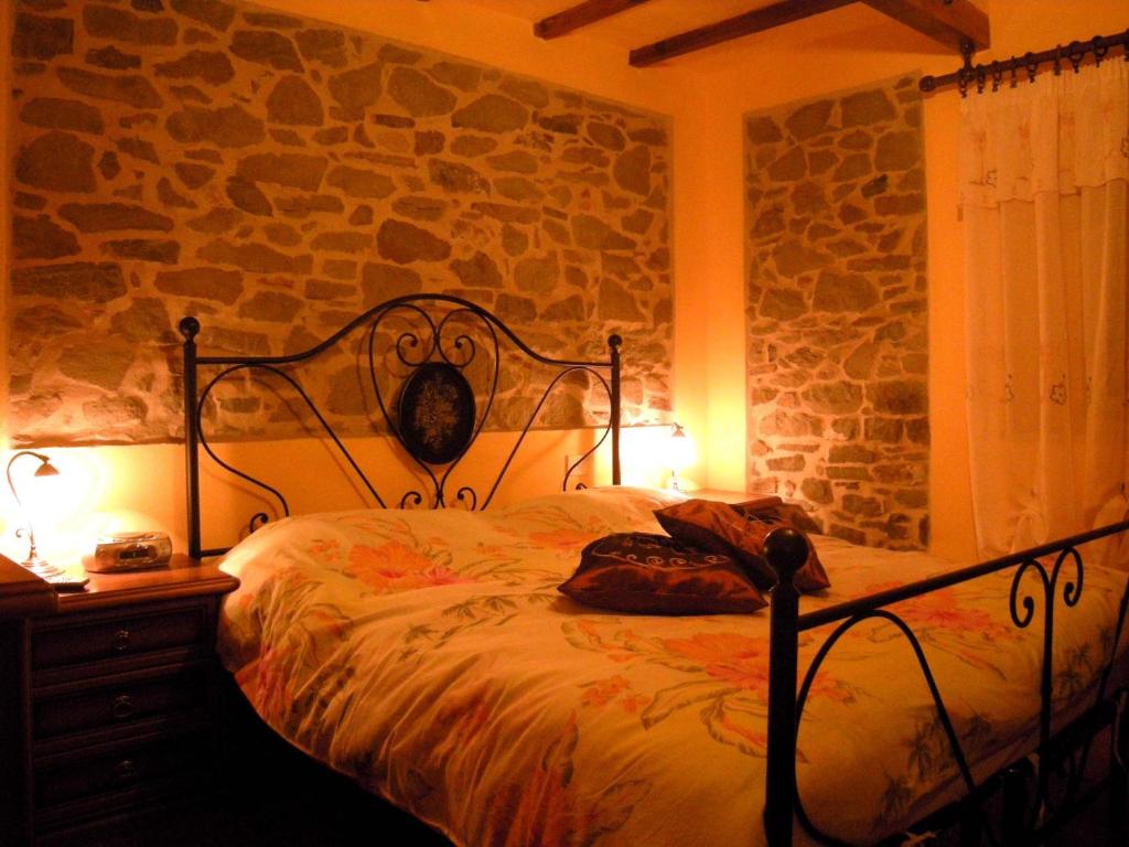 1 dormitorio con cama y pared de piedra en Casa Elisa, en Bibbiena