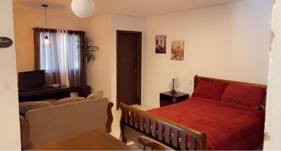 een slaapkamer met een rood bed en een woonkamer bij Flat Deluxe Gramado in Gramado