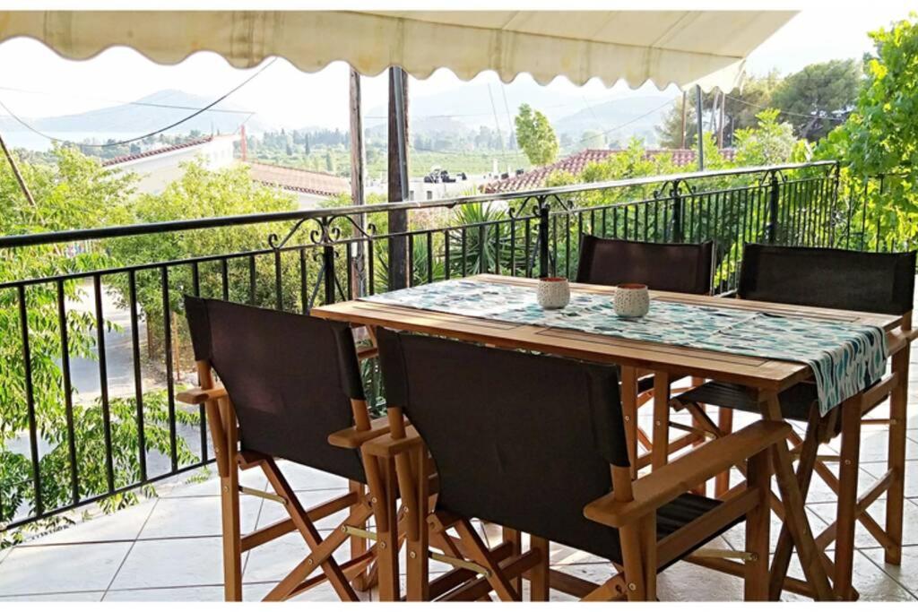 y balcón con mesa y sillas de madera. en Top of the hill in Drepano-Nafplio, Beautiful view, en Dhrepanon