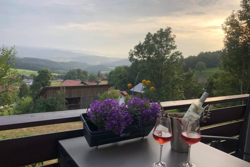 a table with two glasses of wine and a basket of flowers at Apartment Tälerblick in Böbrach