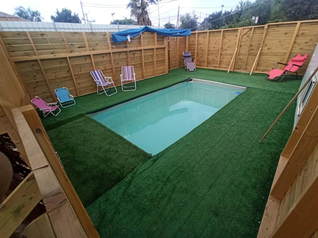 una piscina con césped y sillas en un patio trasero en באוירה יהודית, en H̱azon