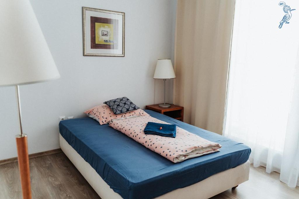 um quarto com uma cama com lençóis azuis e uma janela em Dudok House em Žilina