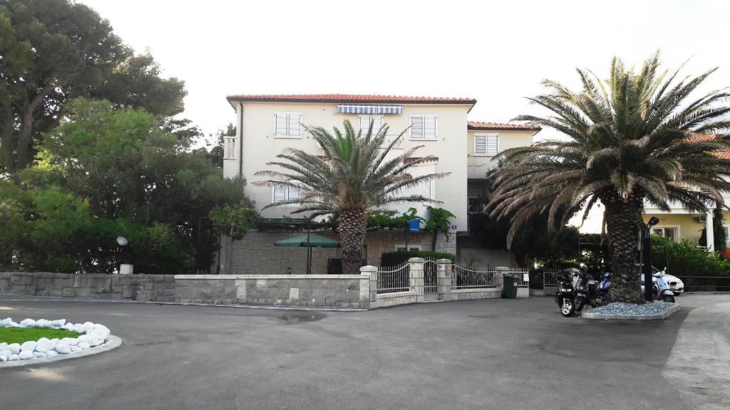 a motorcycle parked in front of a building with palm trees at Villa Ban in Podgora