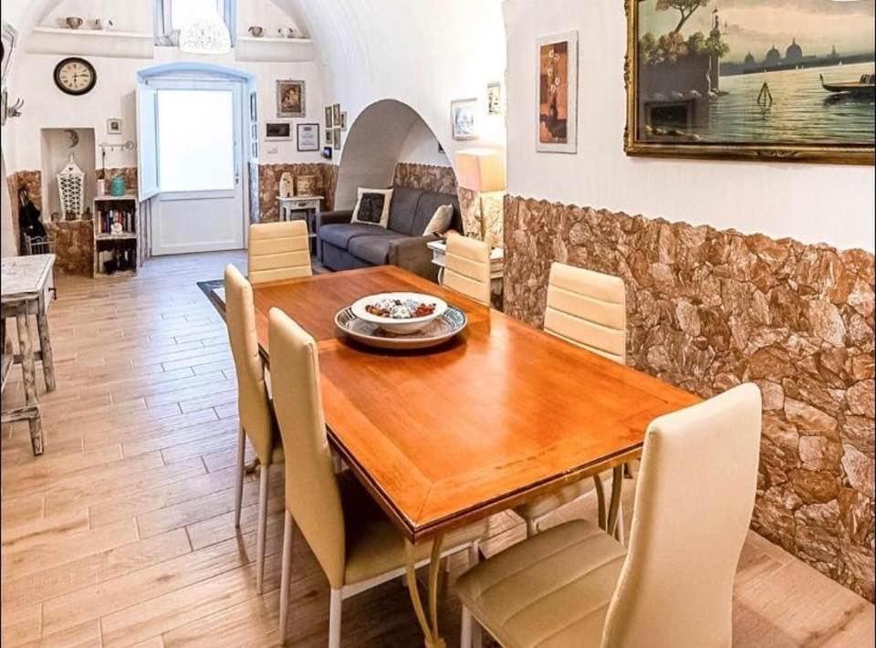 uma sala de jantar com uma mesa de madeira e cadeiras em Dimora luxury Santa Lucia Apartaments em Galatone