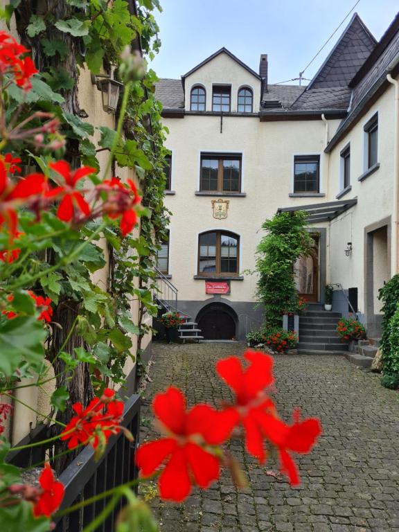 una casa con flores rojas delante de ella en Ferienhaus Winzerauszeit en Ellenz-Poltersdorf
