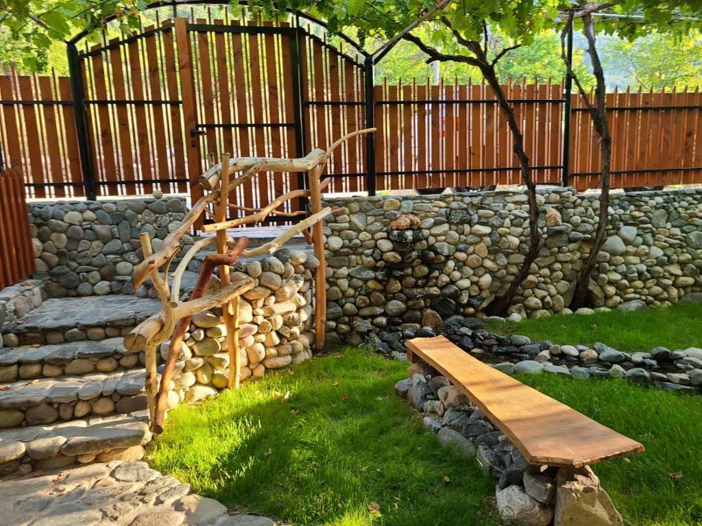 a stone retaining wall with a bench and a fence at Вила 111 in Sapareva Banya