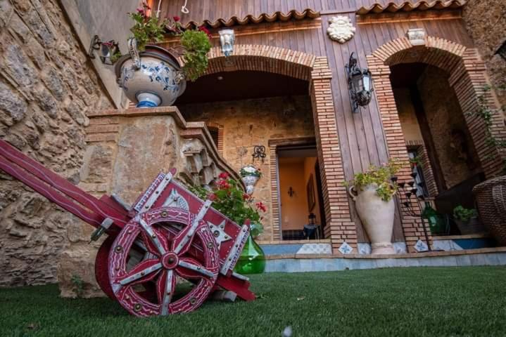 una rueda de madera roja delante de un edificio en Kimera, en Piazza Armerina