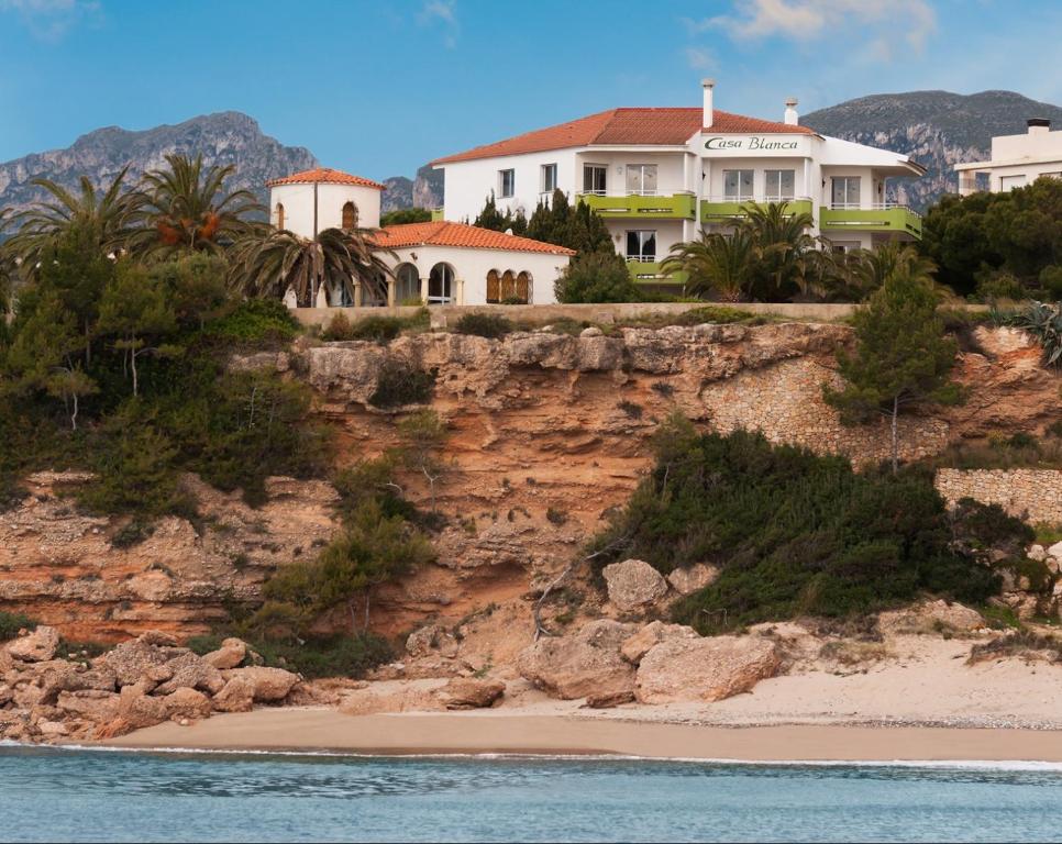 a house on a cliff next to a beach at Apartamentos Casa Blanca in Miami Platja