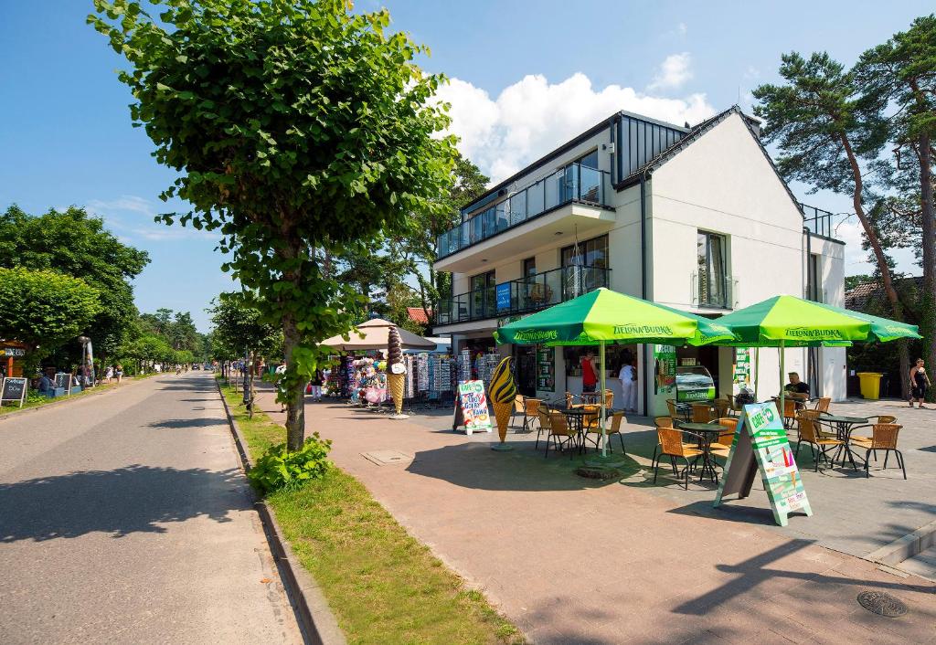 a cafe with green umbrellas and tables on a street at Baltic Harmony Pobierowo Grunwaldzka in Pobierowo