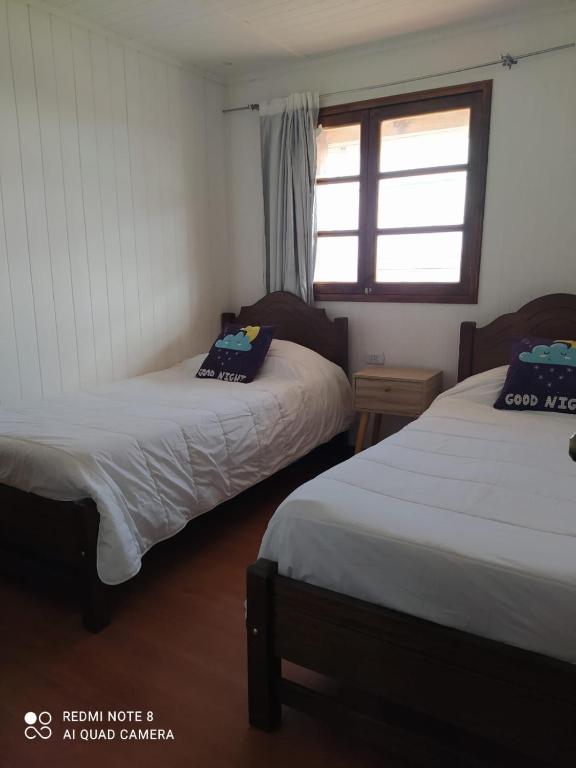 two beds in a room with a window at APARTAMENTO ESPERANZA in Taltal