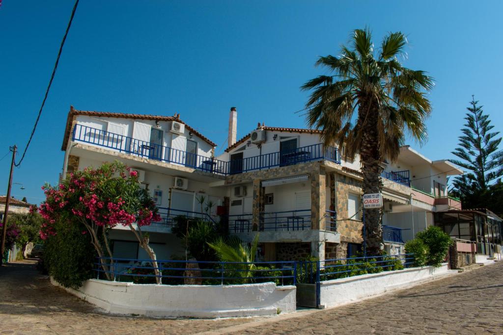 a white building with a palm tree in front of it at Efterpi Aggeli in Loutrópolis Thermís