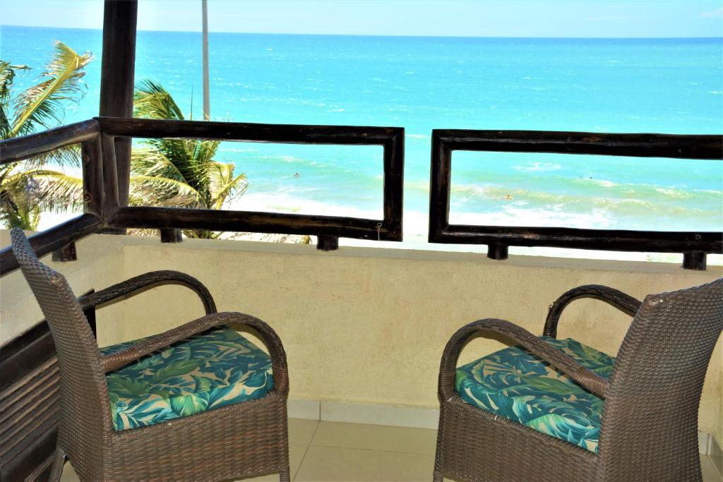 two chairs on a balcony with a view of the beach at Apartamento a Beira Mar no Flat Elegance in Natal