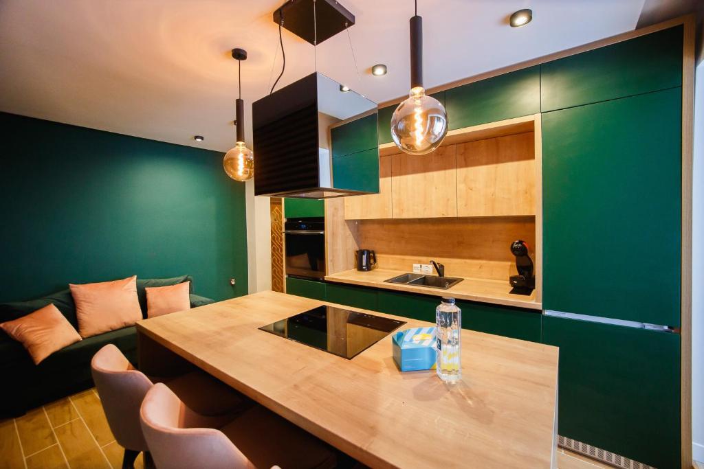 uma cozinha com paredes verdes e uma mesa de madeira em Green Velvet City Retreat em Oradea