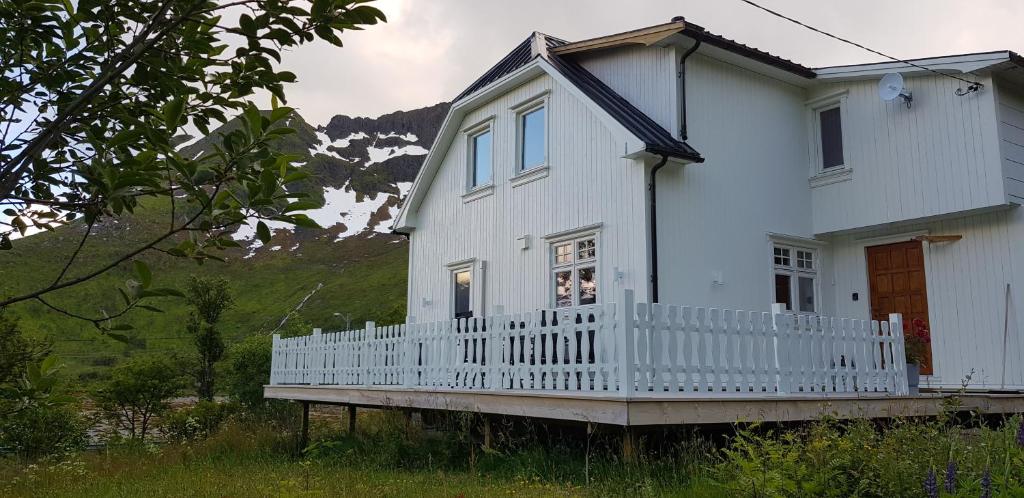 ein weißes Haus mit einer Veranda und einem Berg in der Unterkunft Pilan Lodge Lofoten in Vestpollen