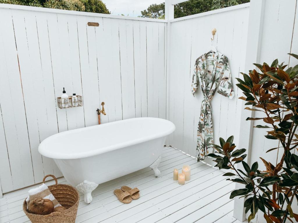 a white bathroom with a bath tub on a white fence at Pineapple Studio Byron Bay in Byron Bay