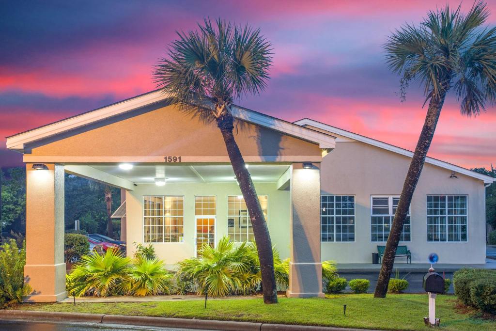 uma casa com duas palmeiras em frente em SureStay Hotel by Best Western North Myrtle Beach em Myrtle Beach