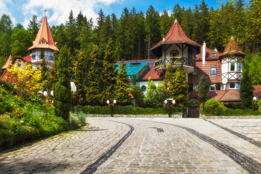 Fairytale-like resort building with turrets behind manicured gardens and cobbled driveway on sunny day.