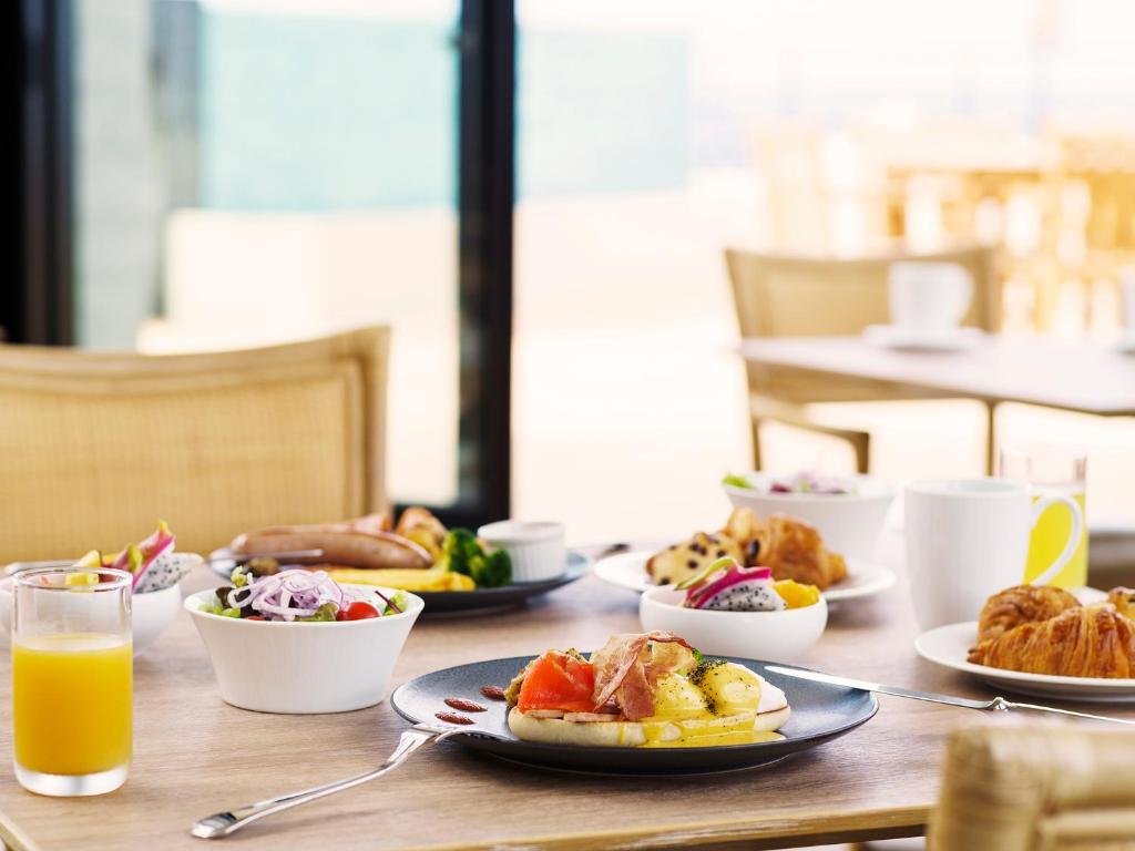 a table with plates of food and a glass of orange juice at MB GALLERY CHATAN by THE TERRACE HOTELS in Chatan