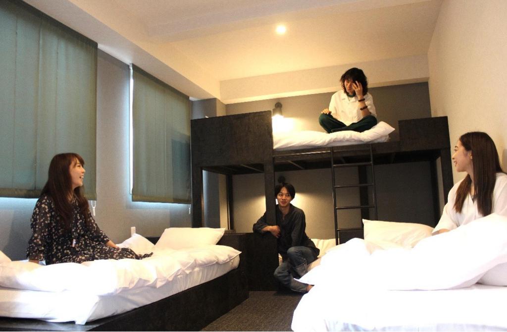 Tres mujeres sentadas en literas en una habitación en DOYANEN HOTELS BAKURO, en Osaka