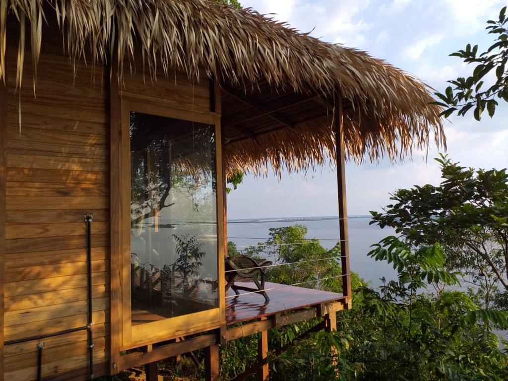 a hut with a large window and a view of the water at Alta Vista Amazon Lodge in Manacapuru