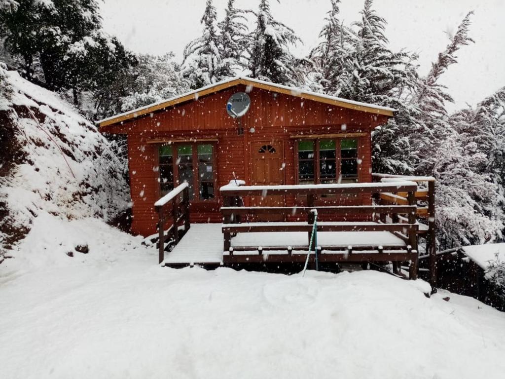 a cabin in the snow with a bench in front at Cabañas Lomas del Manzano in San José de Maipo