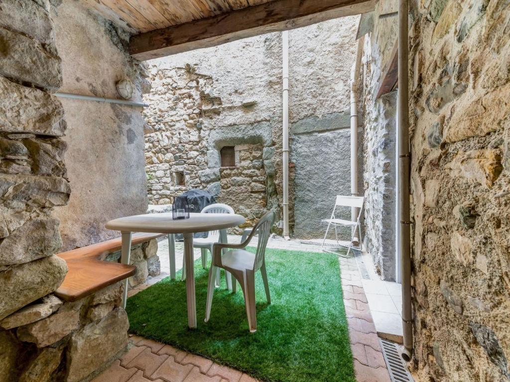 Apartment near the river in Bize Minervois في Bize-Minervois: طاولة وكراسي في غرفة بجدار حجري