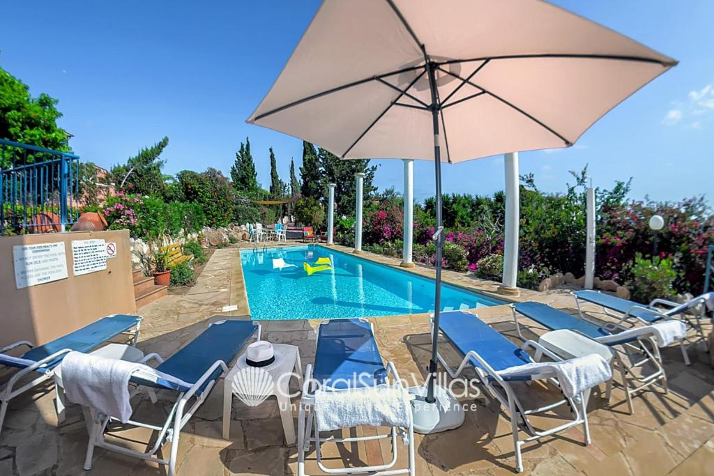 a swimming pool with chairs and an umbrella at Wonderful quiet area,Complete Privacy,Large Pool, Colorful Garden, jacuzzi/Sauna in Peyia