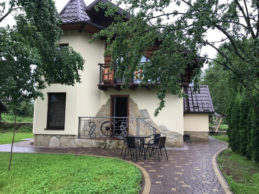 una casa con una mesa y sillas frente a ella en Цісарка en Mykulychyn