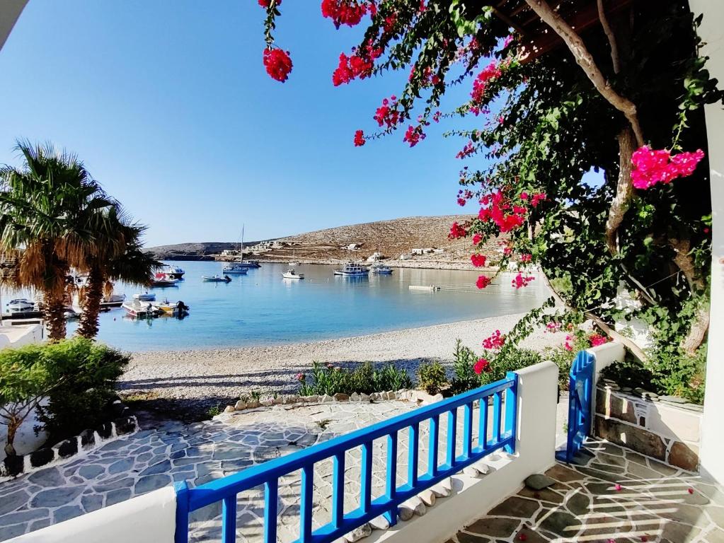uma vista para uma praia com uma cerca azul e flores em Family house by the seaside of Karavostasis em Karavostasi