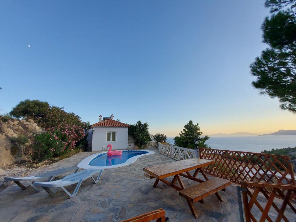 a backyard with a pool and benches and a house at Beautiful house located on a hill, with a spectacular sea view in Koumeika