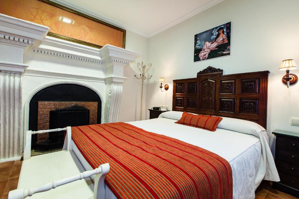 a bedroom with a large bed and a fireplace at Hotel Palacio del Intendente in Guarromán