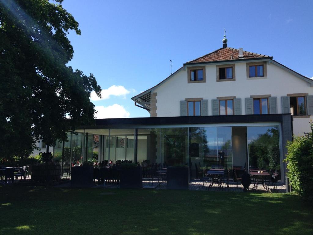 een groot wit huis met een glazen verlenging bij Auberge de Confignon in Genève