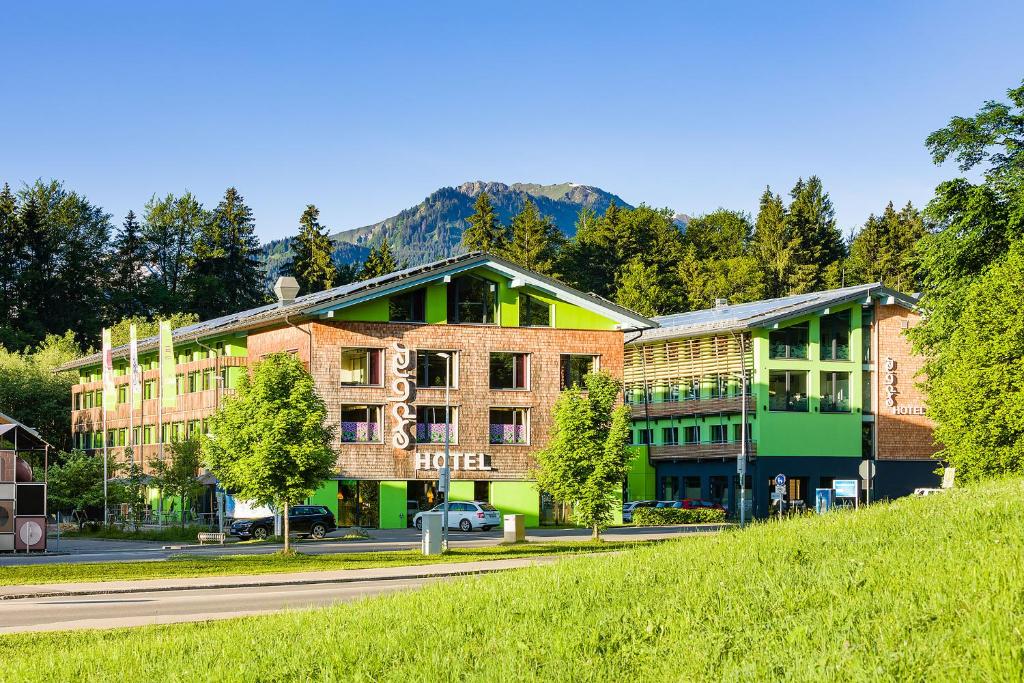 ein Gebäude auf einer Straße mit einem Berg im Hintergrund in der Unterkunft Explorer Hotel Oberstdorf in Fischen im Allgäu