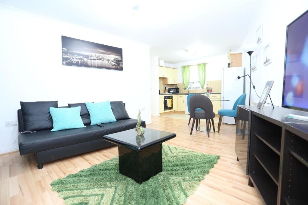 a living room with a black couch and a table at 2 Bedroom Apartment in Thamesmead