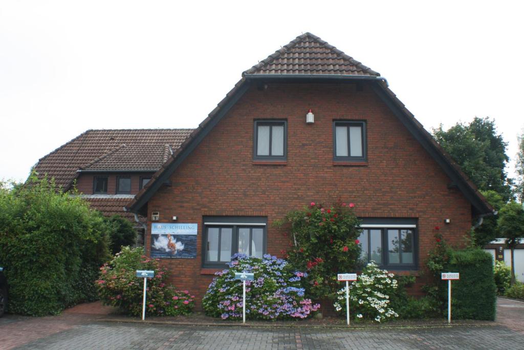 ein rotes Backsteinhaus mit Blumen davor in der Unterkunft Haus Schilling in Esens