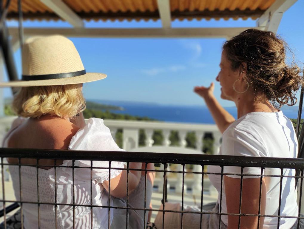 Dos mujeres están mirando el océano desde un balcón en Apartments Barisic Hrvatskih Žrtava 404 Seget Vranjica, en Trogir