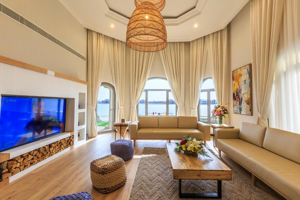 a living room with two couches and a tv at The S Holiday Homes - Stunning 5 Bedrooms Villa at the Palm Jumeirah with Private Beach and Pool in Dubai